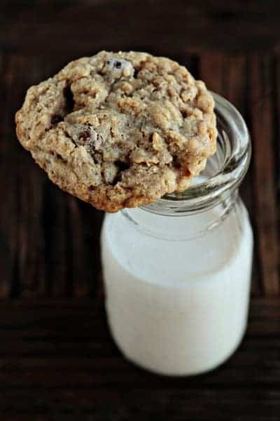 An oatmeal raisinet cookie on top of a glass of milk