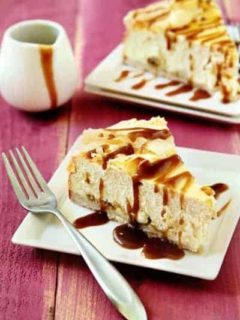 Two slices of rum raisin cheesecake on plates with forks on a red wood surface