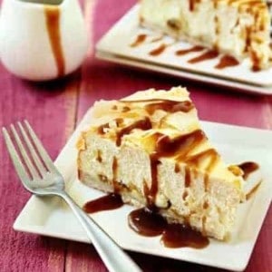 Two slices of rum raisin cheesecake on plates with forks on a red wood surface