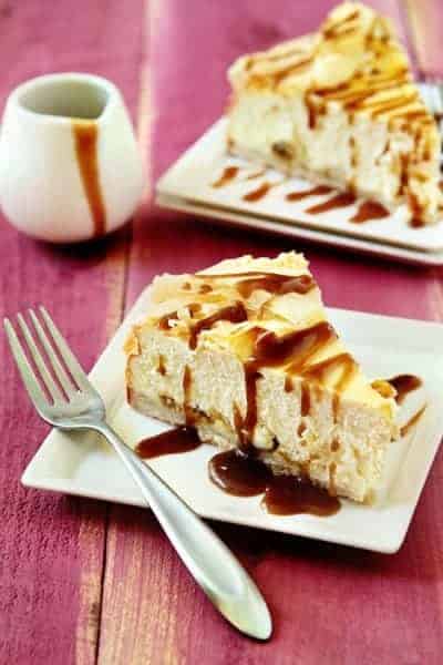 Two slices of rum raisin cheesecake on plates with forks on a red wood surface