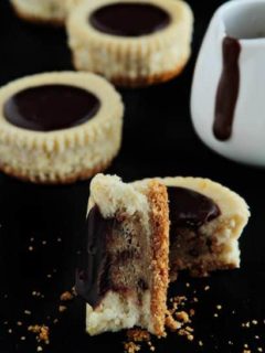 Individual cookie dough cheesecake cut in half on a black surface