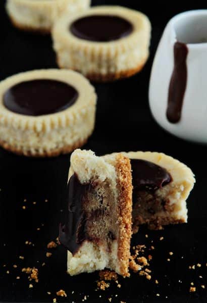 Individual cookie dough cheesecake cut in half on a black surface