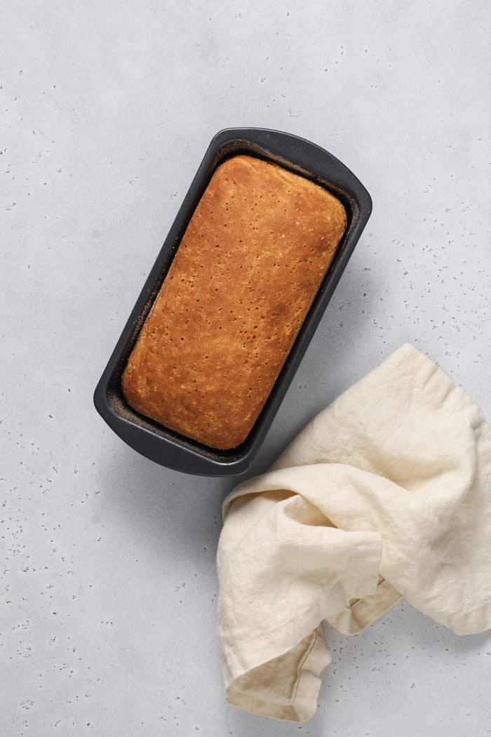 Baked loaf of english muffin bread cooling on a light colored countertop