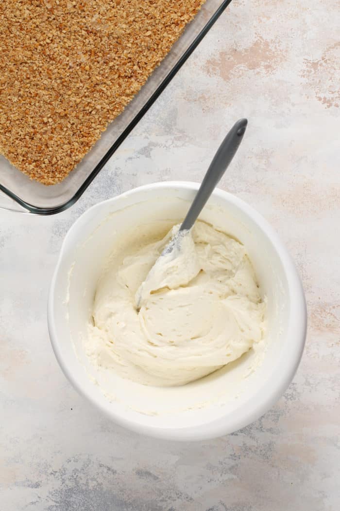 Cream cheese filling for strawberry pretzel salad in a white mixing bowl.