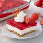 Slice of strawberry pretzel salad garnished with whipped cream, strawberries, and a pretzel.