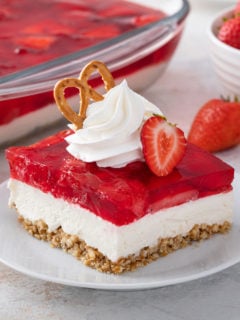 Slice of strawberry pretzel salad garnished with whipped cream, strawberries, and a pretzel.