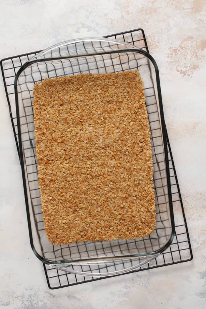 Baked pretzel crust in a glass baking dish set on a wire cooling rack.