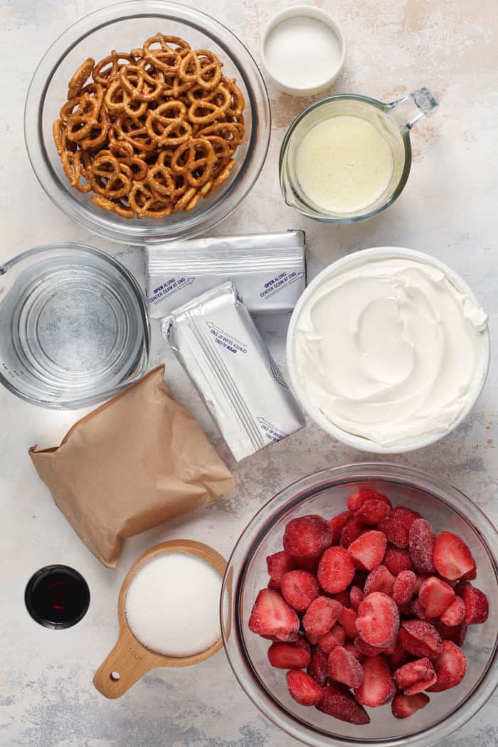 Ingredients for strawberry pretzel salad arranged on a light-colored surface.
