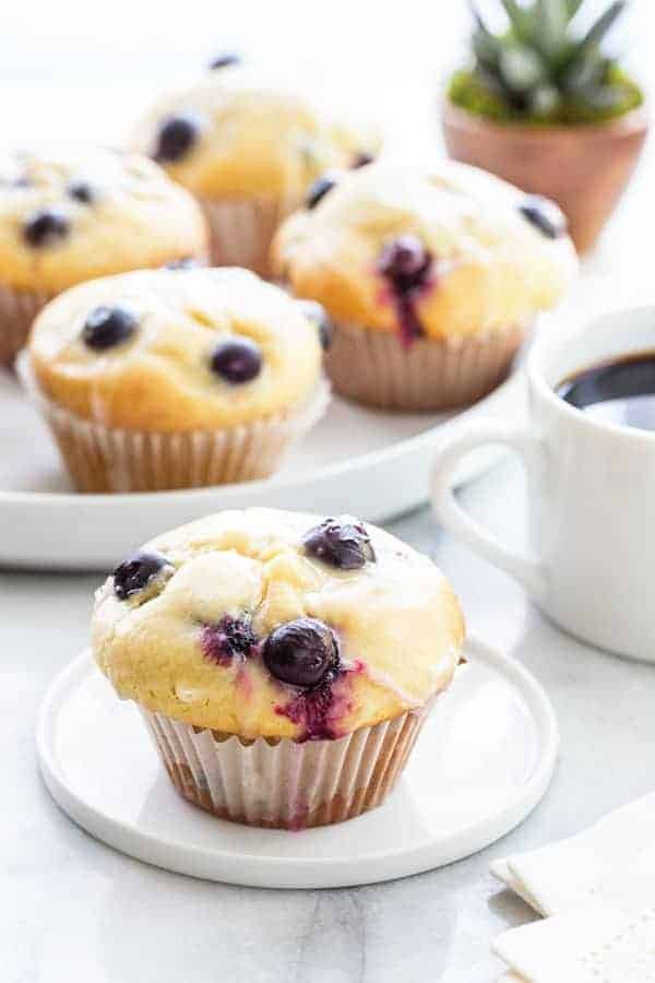 Blueberry Doughnut Muffins bake up high and mighty and are topped with a sweet and tangy lemon glaze.  So perfect for summer!