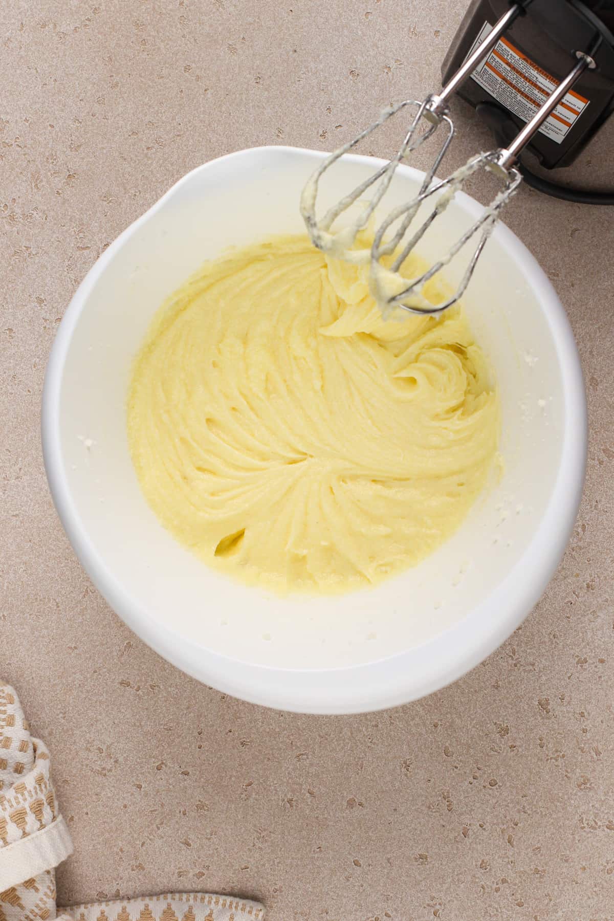 Butter, sugar, and eggs mixed together in a white mixing bowl.