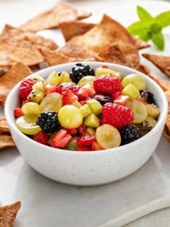 White bowl of fruit salsa with cinnamon chips in the background.