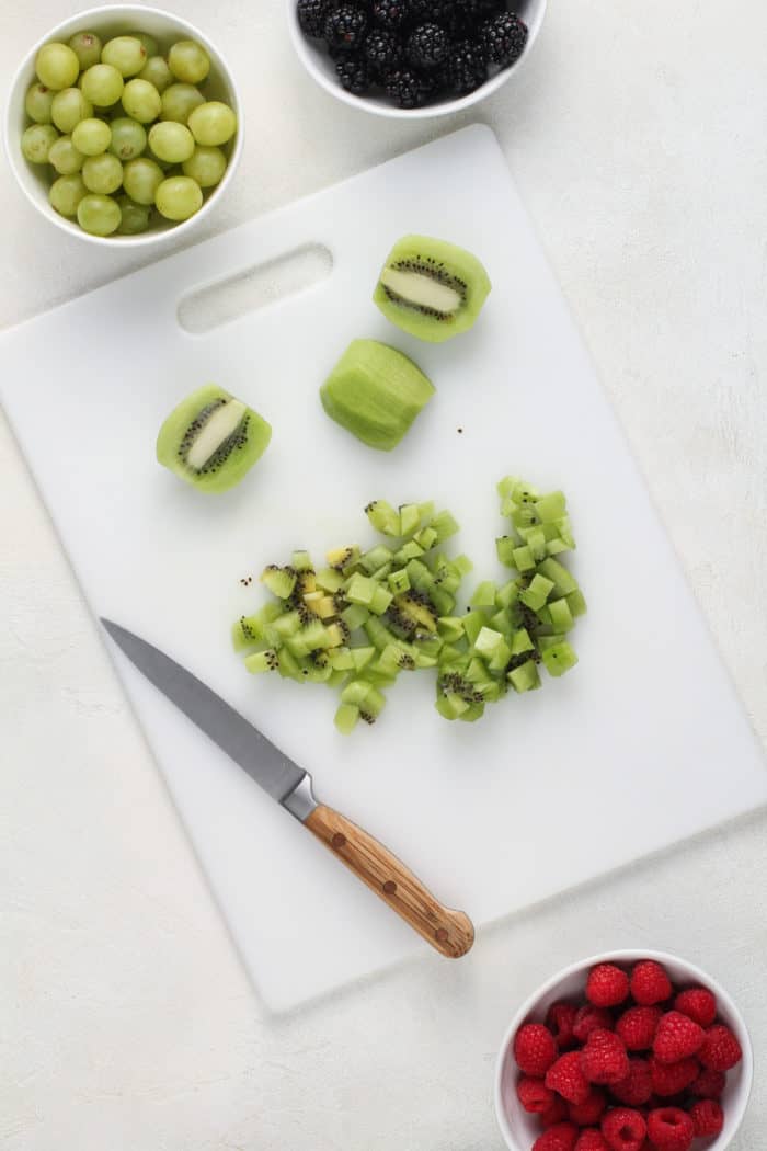 Diced kiwi on a white cutting board.