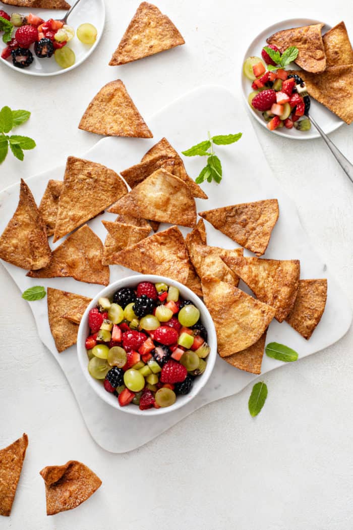 Overhead view of a bowl of fruit salsa surrounded by cinnamon chips.