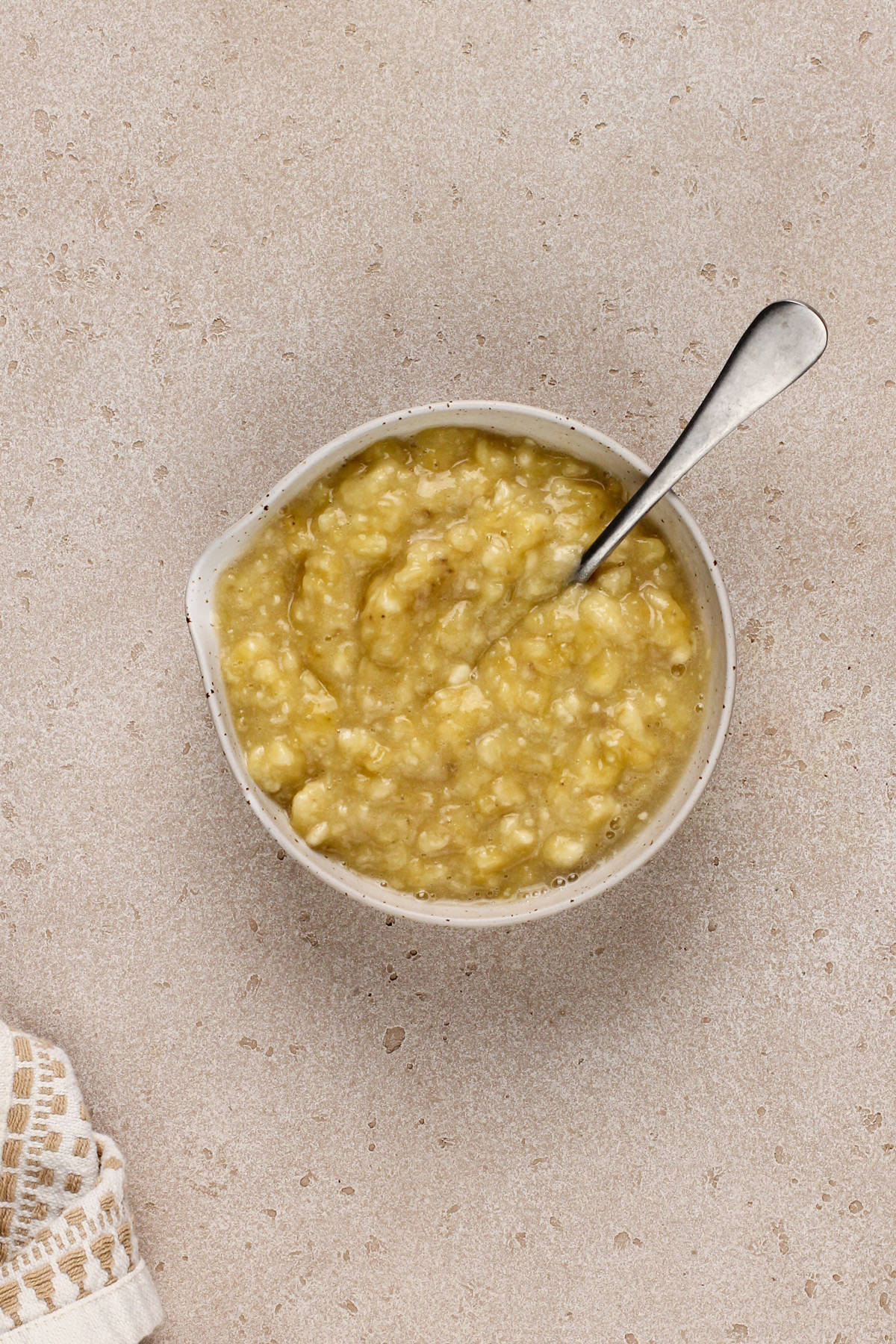 Mashed bananas in a white bowl.