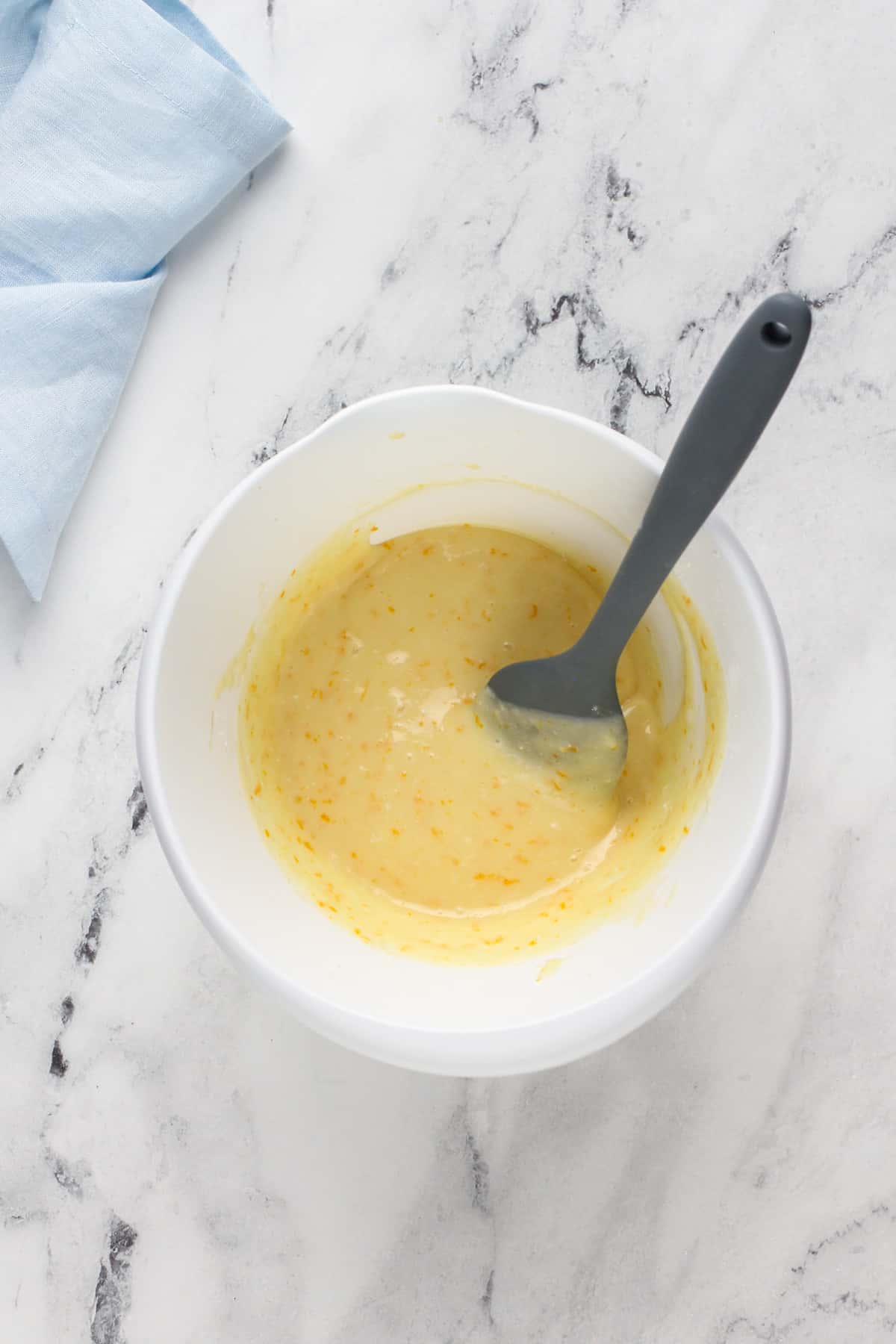 Orange cream cheese glaze in a white mixing bowl.