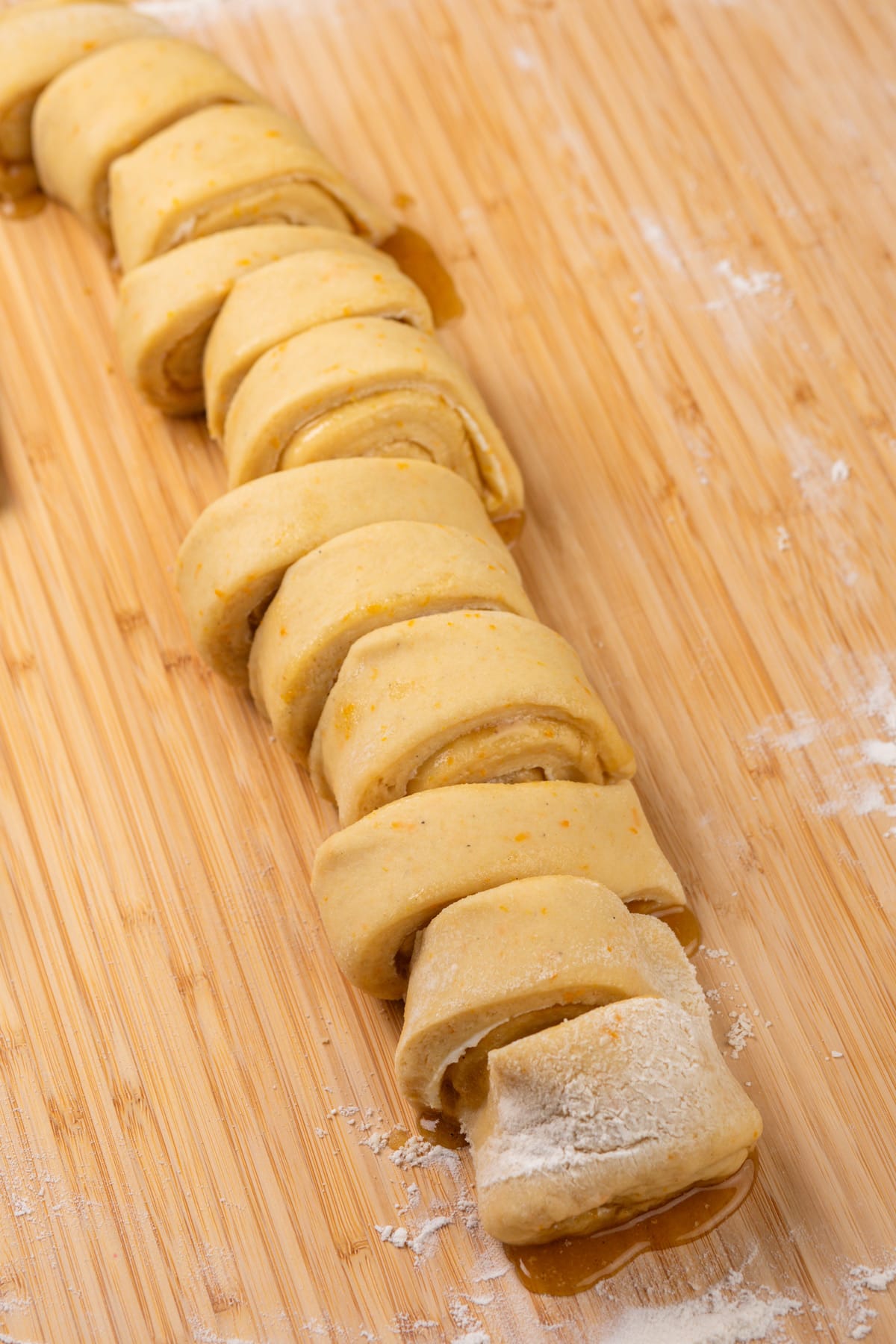 Rolled and sliced orange rolls, ready to be placed in a baking dish.