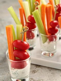 Small shot glasses full of dill dip and assorted veggies
