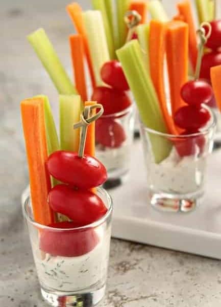 Small shot glasses full of dill dip and assorted veggies