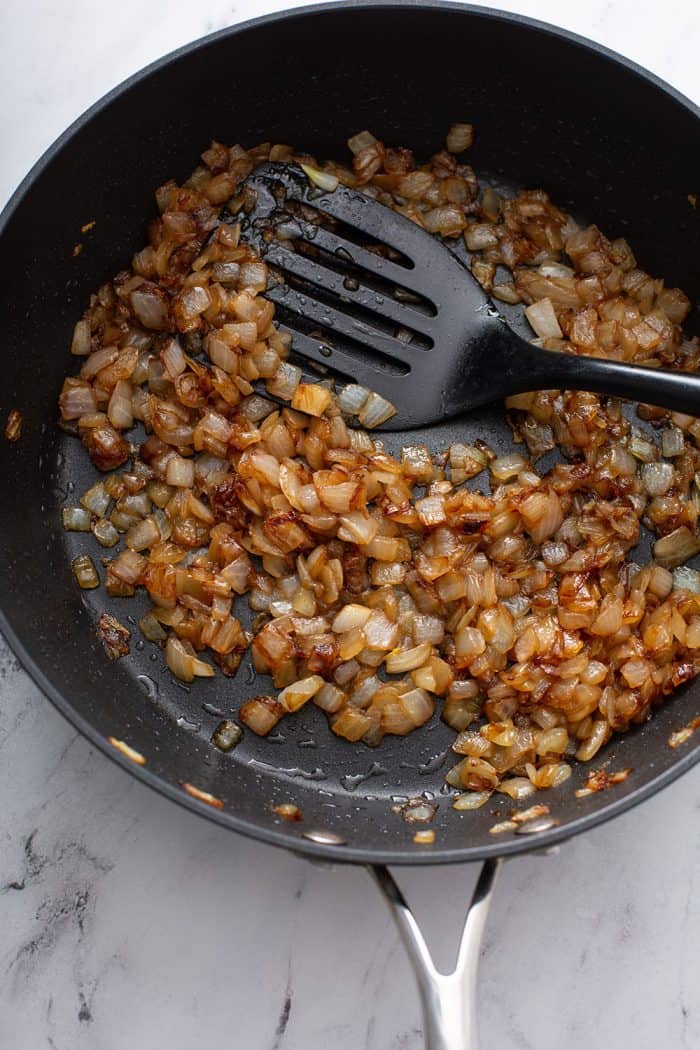 Caramelized onions in a skillet on a marble counter