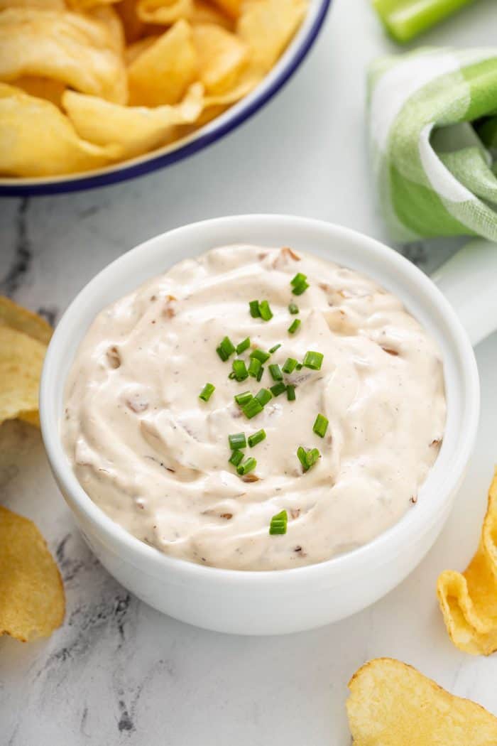French onion dip in a white bowl on a counter with potato chips