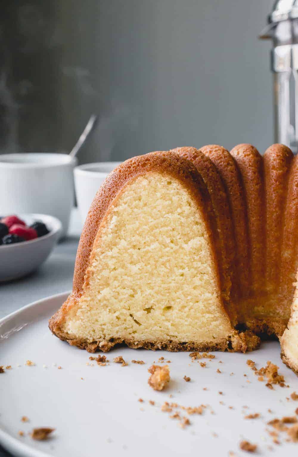 Sliced 7up pound cake on a cake plate in front of a bowl of berries