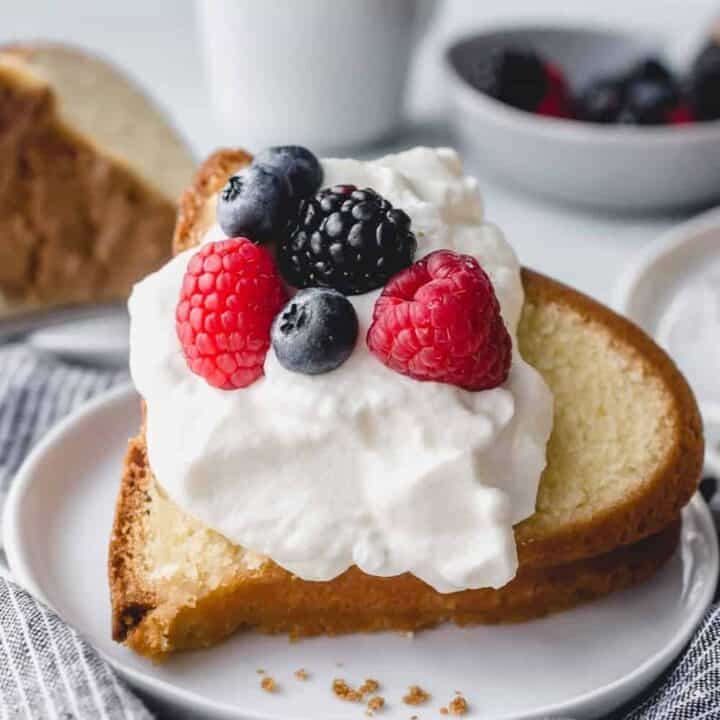 Close up of a slice of 7up pound cake topped with whipped cream and fresh berries