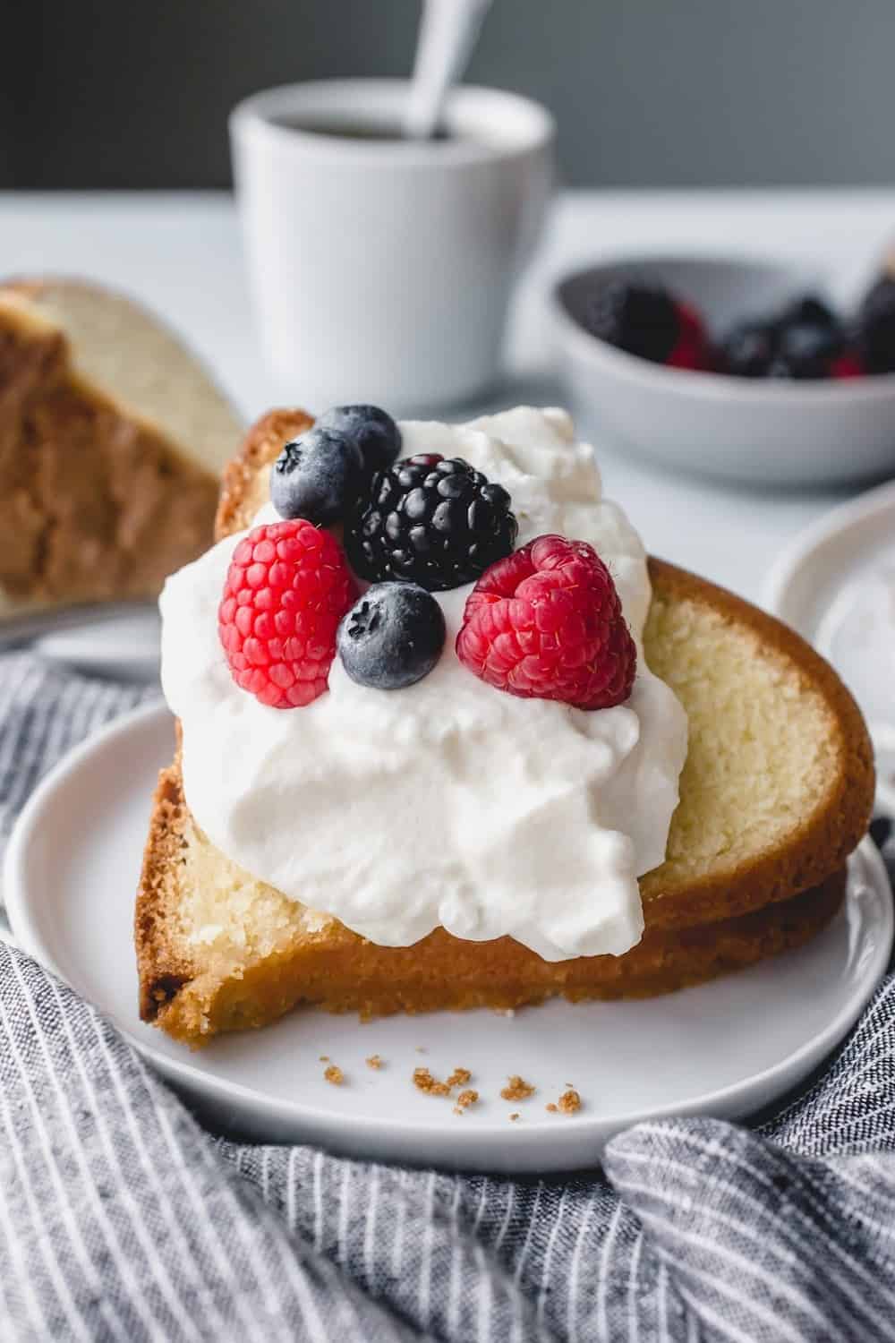 Close up of a slice of 7up pound cake topped with whipped cream and fresh berries