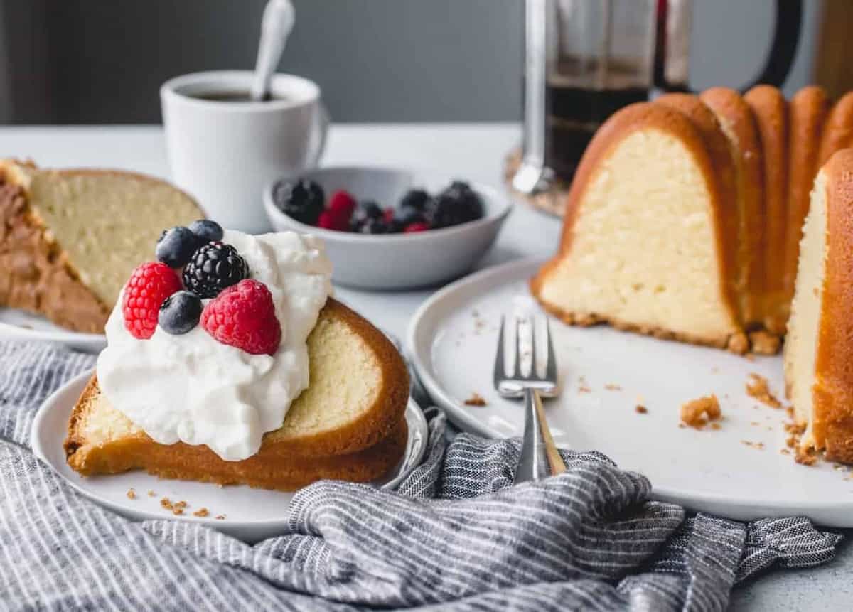 Plated slice of 7up pound cake next to the full cake on a cake plate