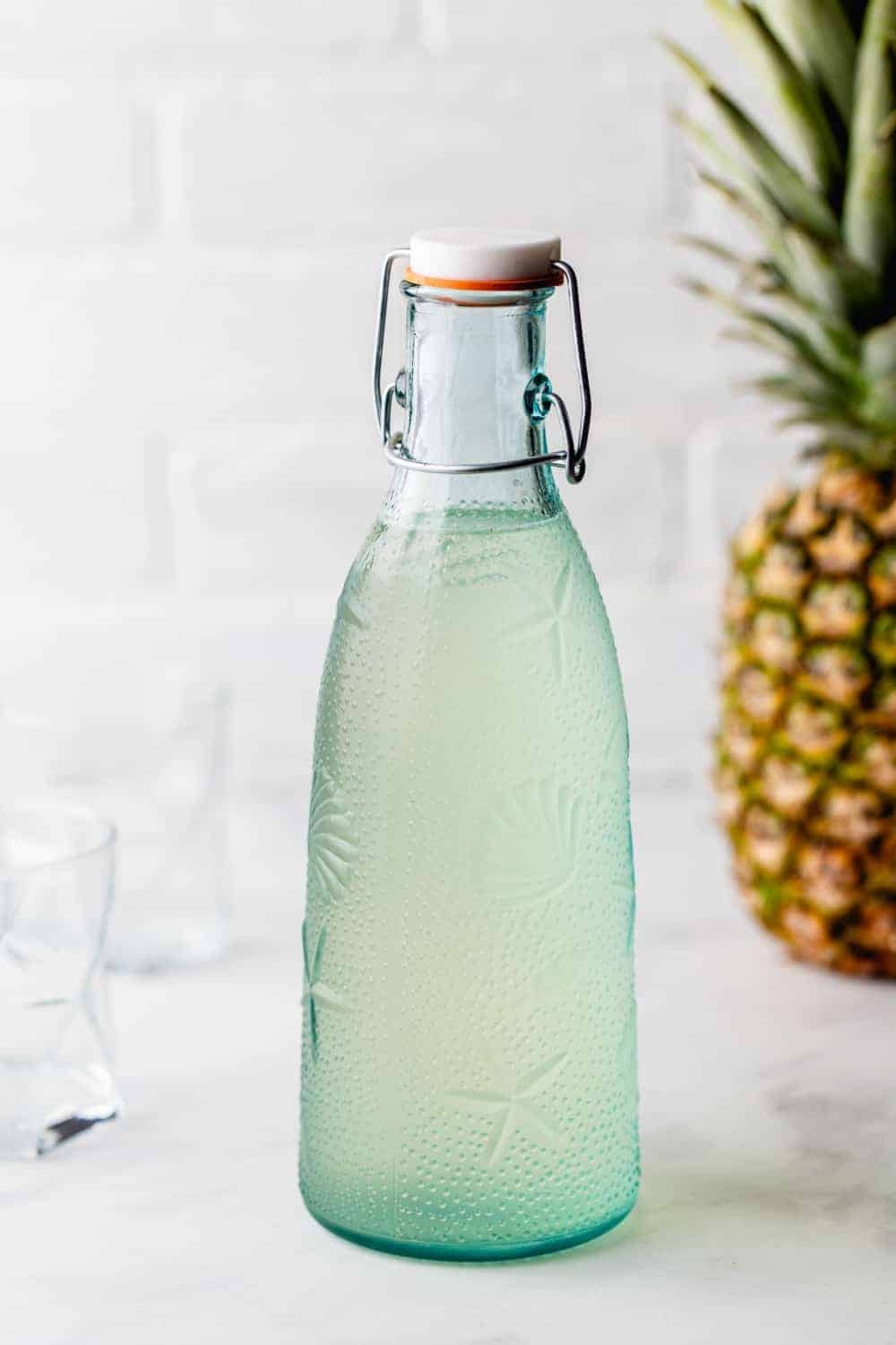 fles ananas-infused wodka met een ananas op de achtergrond