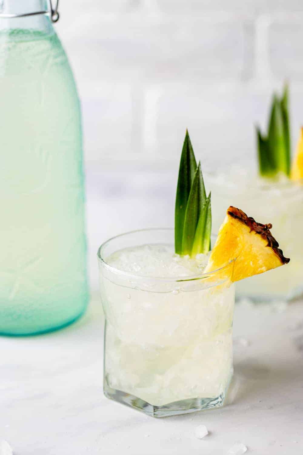 Stoli Doli in a rocks glass next to a bottle of pineapple vodka