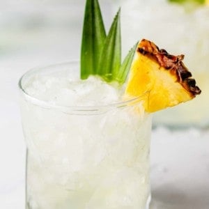 Pineapple vodka in a rocks glass, garnished with a slice of pineapple