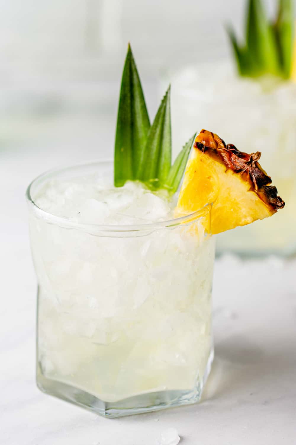 Pineapple vodka in a rocks glass, garnished with a slice of pineapple