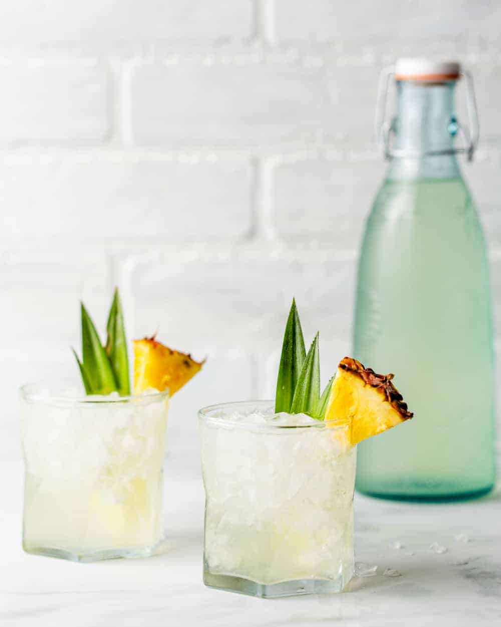 twee Stoli Doli cocktails in stenen glazen naast een fles geÃ nfundeerde ananas wodka