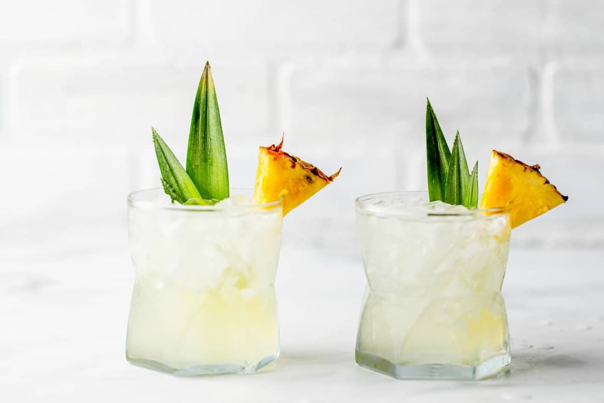 Two glasses of Stoli Doli on the rocks, garnished with pineapple