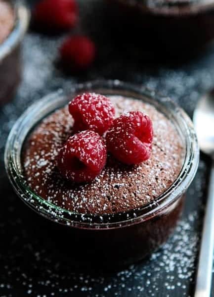 Close up of flourless chocolate cake topped with raspberries and dusted with powdered sugar