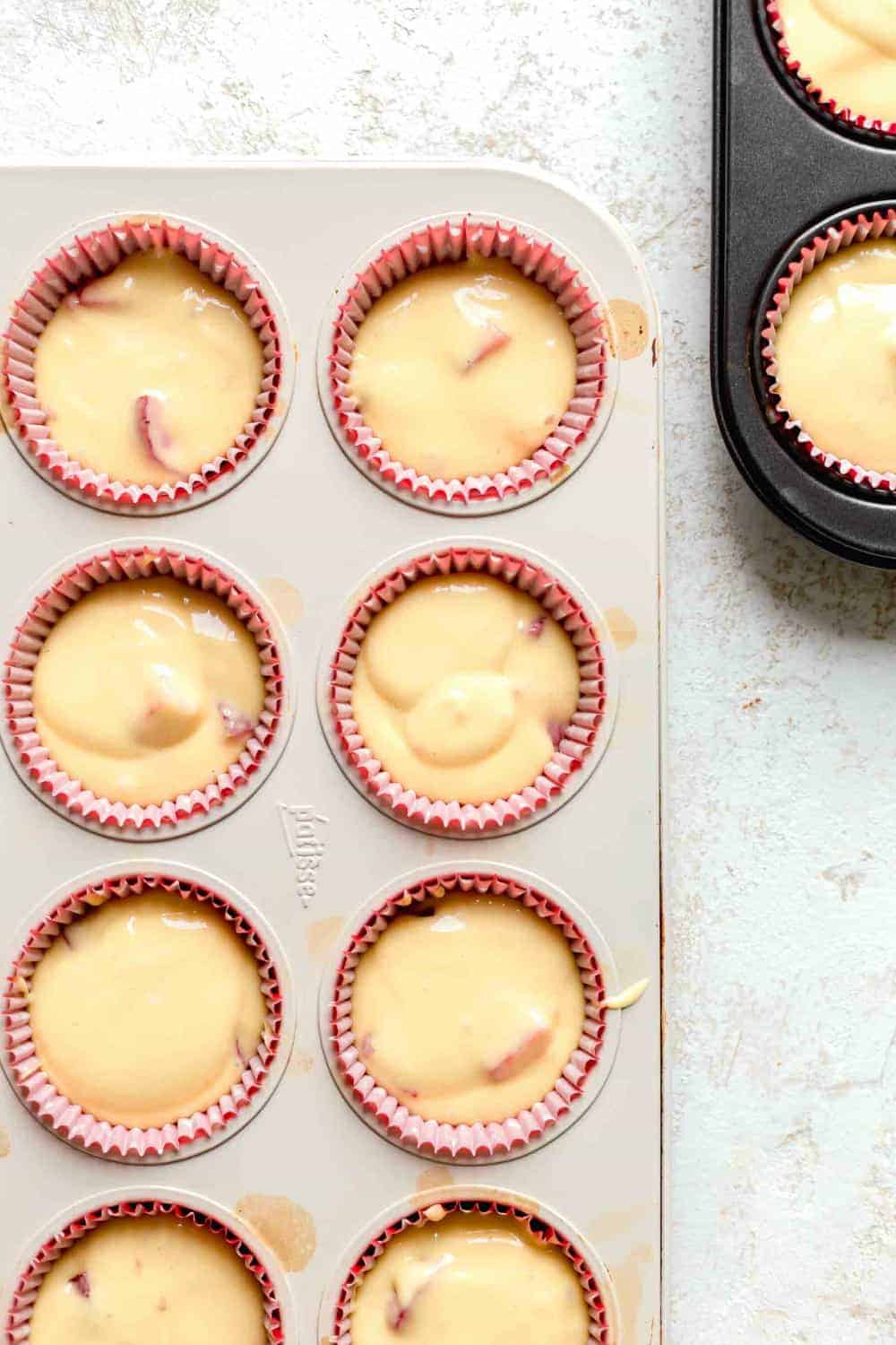 Overhead view of strawberry cupcake batter in red paper liners in cupcake pan