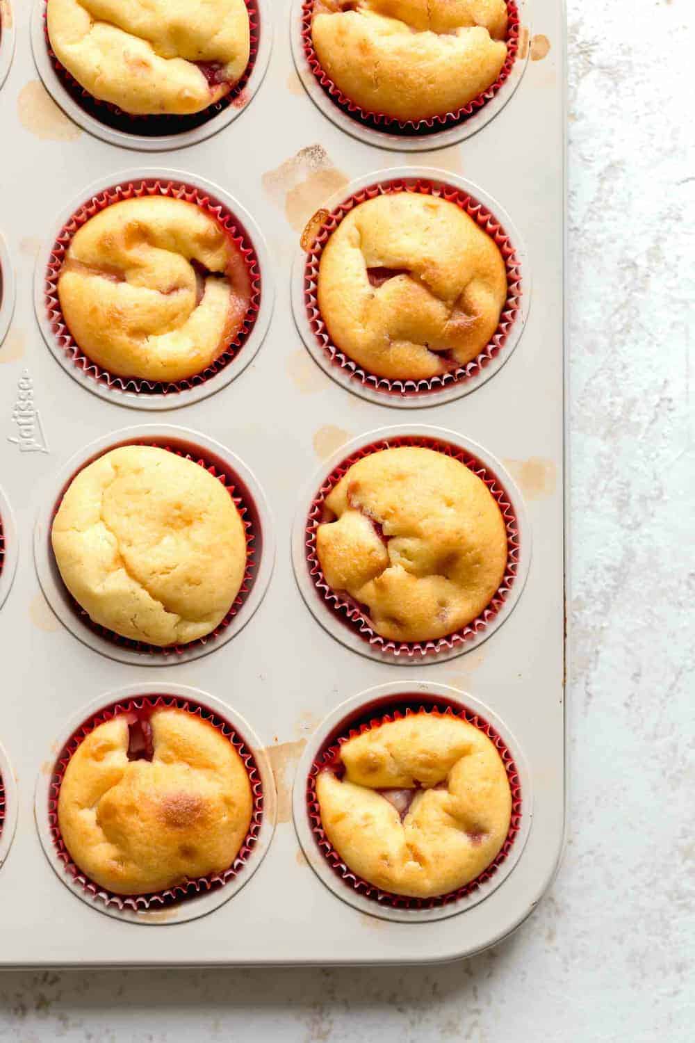 Overhead view of baked strawberry cupcakes in red paper liners in cupcake pan