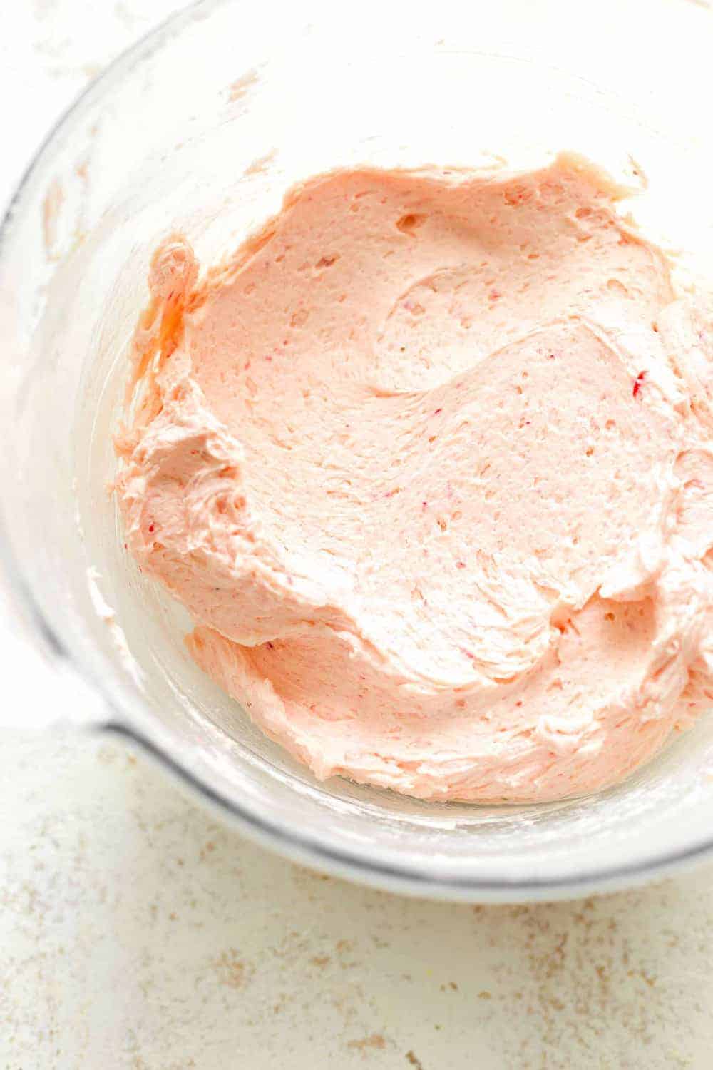 Overhead view of strawberry buttercream frosting in a glass bowl