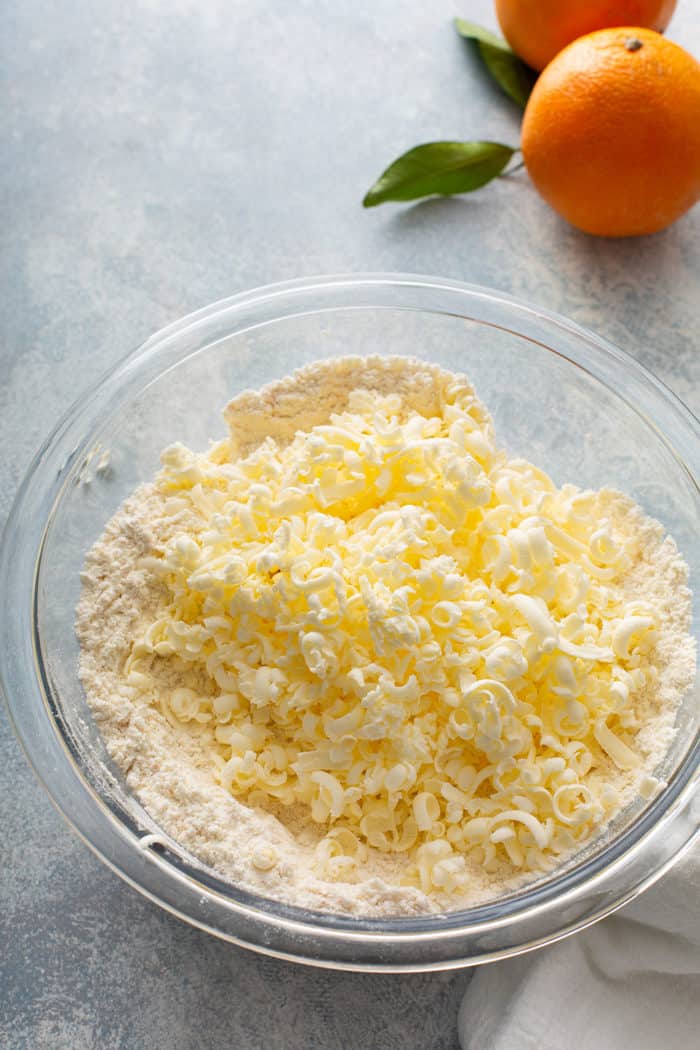 Grated butter added to dry ingredients for scones in a glass mixing bowl