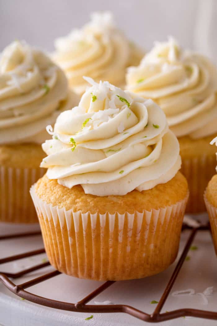 Close up of a coconut cupcake on a platter with other cupcakes.