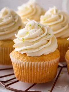 Close up of a coconut cupcake on a platter with other cupcakes.