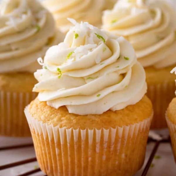 Close up of a coconut cupcake on a platter with other cupcakes.