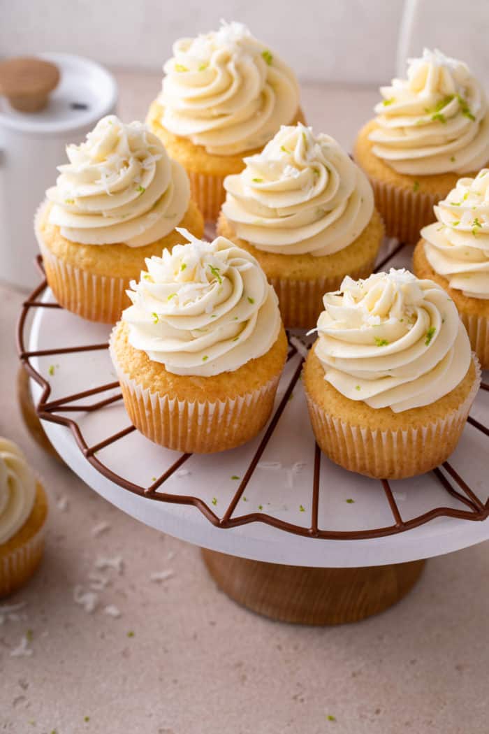 Cake plate filled with coconut cupcakes topped with coconut-lime buttercream.