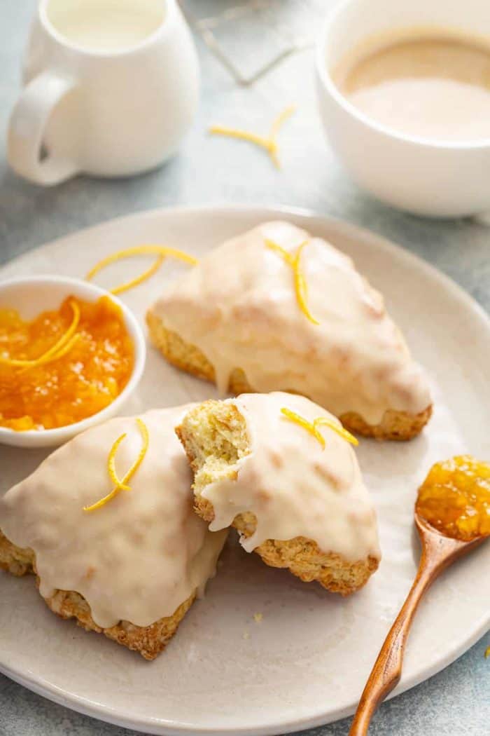 Orange scone with a bite taken out of it stacked on top of two other scones on a white plate