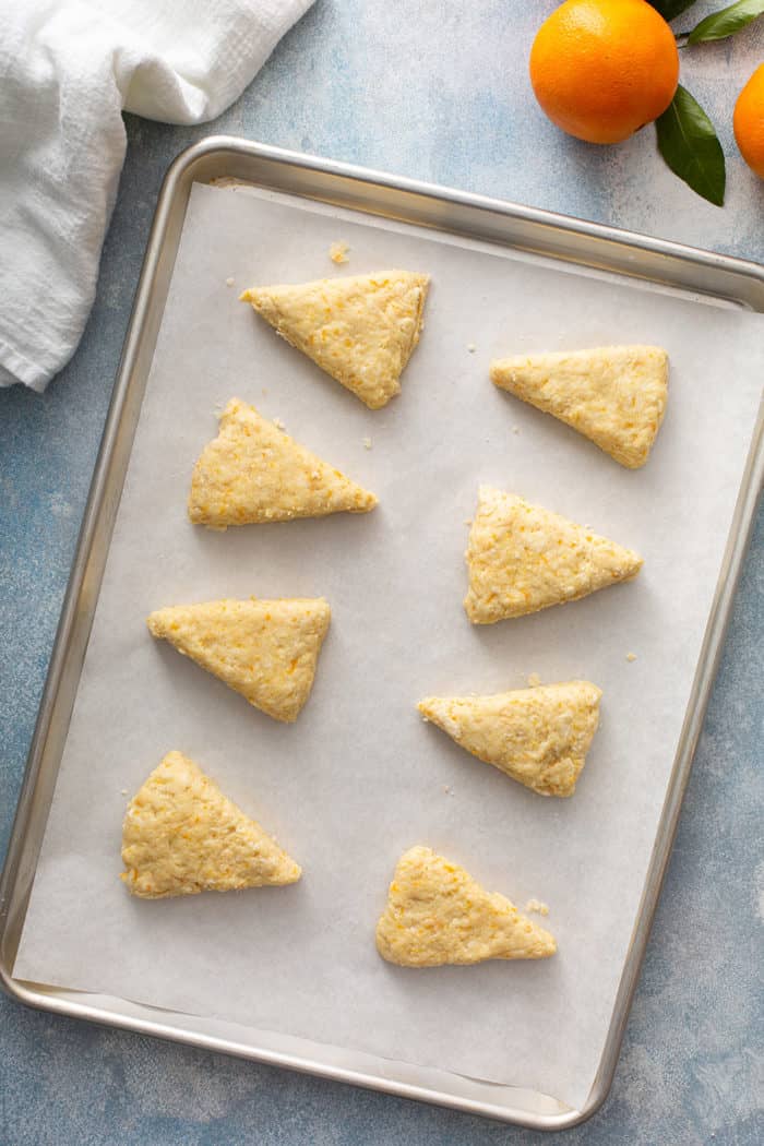 Unbaked orange scones arranged on a parchment-lined baking sheet