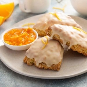 Close up of three orange scones arranged on a white plate