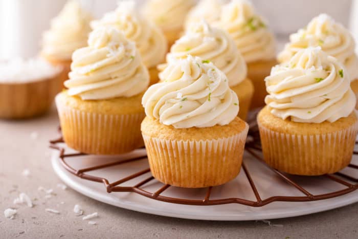 Several coconut cupcakes arranged on a white platter.