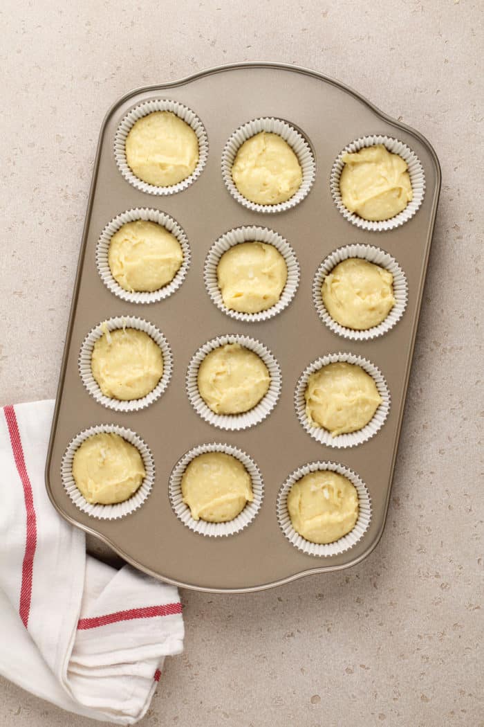 Coconut cupcake batter divided into lined cupcake wells, ready to go in the oven.