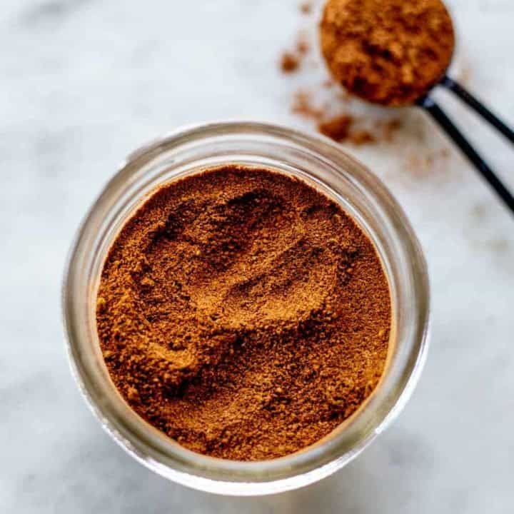 Apple pie spice in a jar next to a measuring spoon