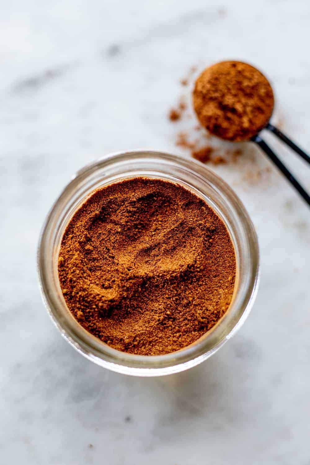 Apple pie spice in a jar next to a measuring spoon